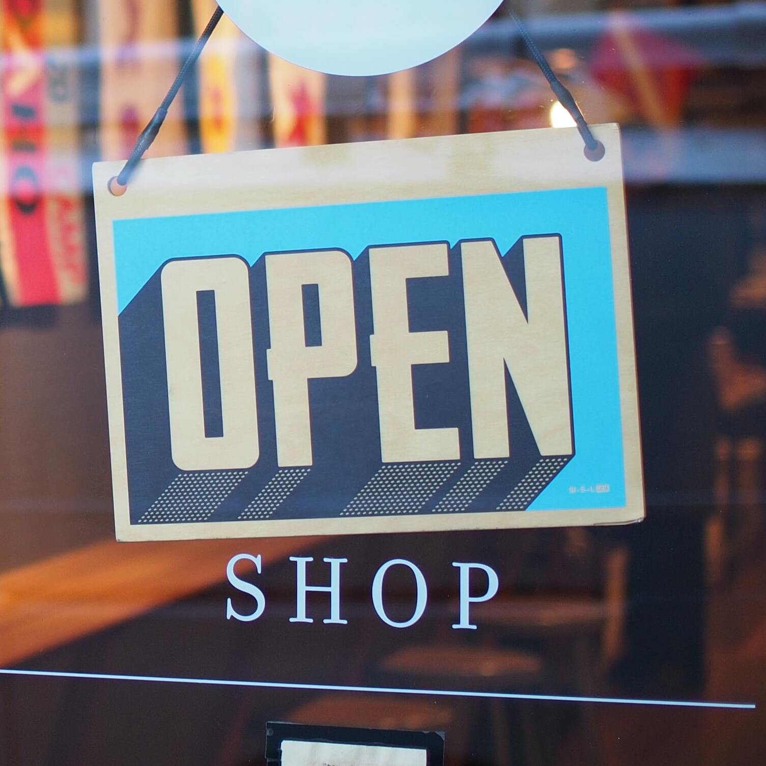 An open sign on the glass door of a shop.